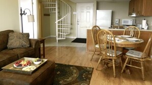 A living room with a brown sofa, a dining table with wooden chairs, and a kitchen area with wooden cabinets and a microwave. - "AMAZING" LONG RANGE MOUNTAIN VEIWS!! Peaceful MountainTop Getaway! (Gatlinburg)