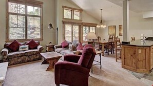 Un salon spacieux doté d’une grande fenêtre, d’une cheminée chaleureuse et d’un coin repas avec des meubles en bois.