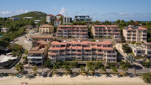 A beachfront hotel with multiple buildings, a sandy beach, and clear turquoise waters. - Grande Bay Resort Condo - Come Stay at 'Sunsets and Breezes' (Cruz Bay)