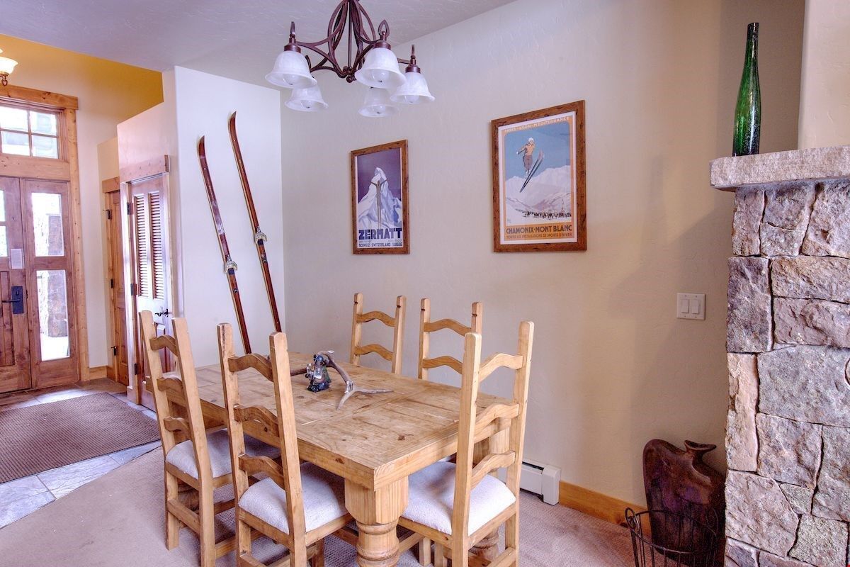 Un comedor con una mesa y sillas de madera, un candelabro y carteles con motivos de esquí en la pared.