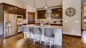 Eine moderne Küche mit Edelstahlgeräten, Holzschränken und einer zentralen Kochinsel mit Barhocker.