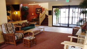 Eine Lobby mit einer Couch, Sesseln, einem Couchtisch, einer Treppe und einer zur Außenseite führenden Tür.