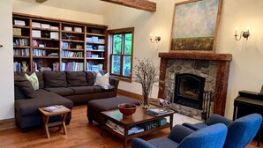 A cozy living room with a fireplace, bookshelves, and comfortable seating. - Meech Lake peaceful retreat (Chelsea)