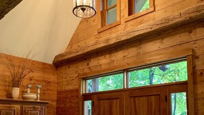 A wooden interior with a large wooden door, a cabinet, and a chair. - Meech Lake peaceful retreat (Chelsea)
