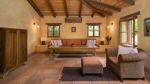 A cozy room with a wooden ceiling, a sofa, a chair, a table, and a cabinet. - Private,Secluded Tamarindo Beach House -DIRECT BEACH ACCESS Perfect for families (Playa Tamarindo)