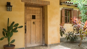 A wooden door with a metal handle, a potted plant, and a small wall-mounted light fixture. - Private,Secluded Tamarindo Beach House -DIRECT BEACH ACCESS Perfect for families (Playa Tamarindo)