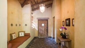 A hallway with a stone floor, a wooden bench with cushions, a small table with a potted plant, and a wooden door at the end. - Private,Secluded Tamarindo Beach House -DIRECT BEACH ACCESS Perfect for families (Playa Tamarindo)