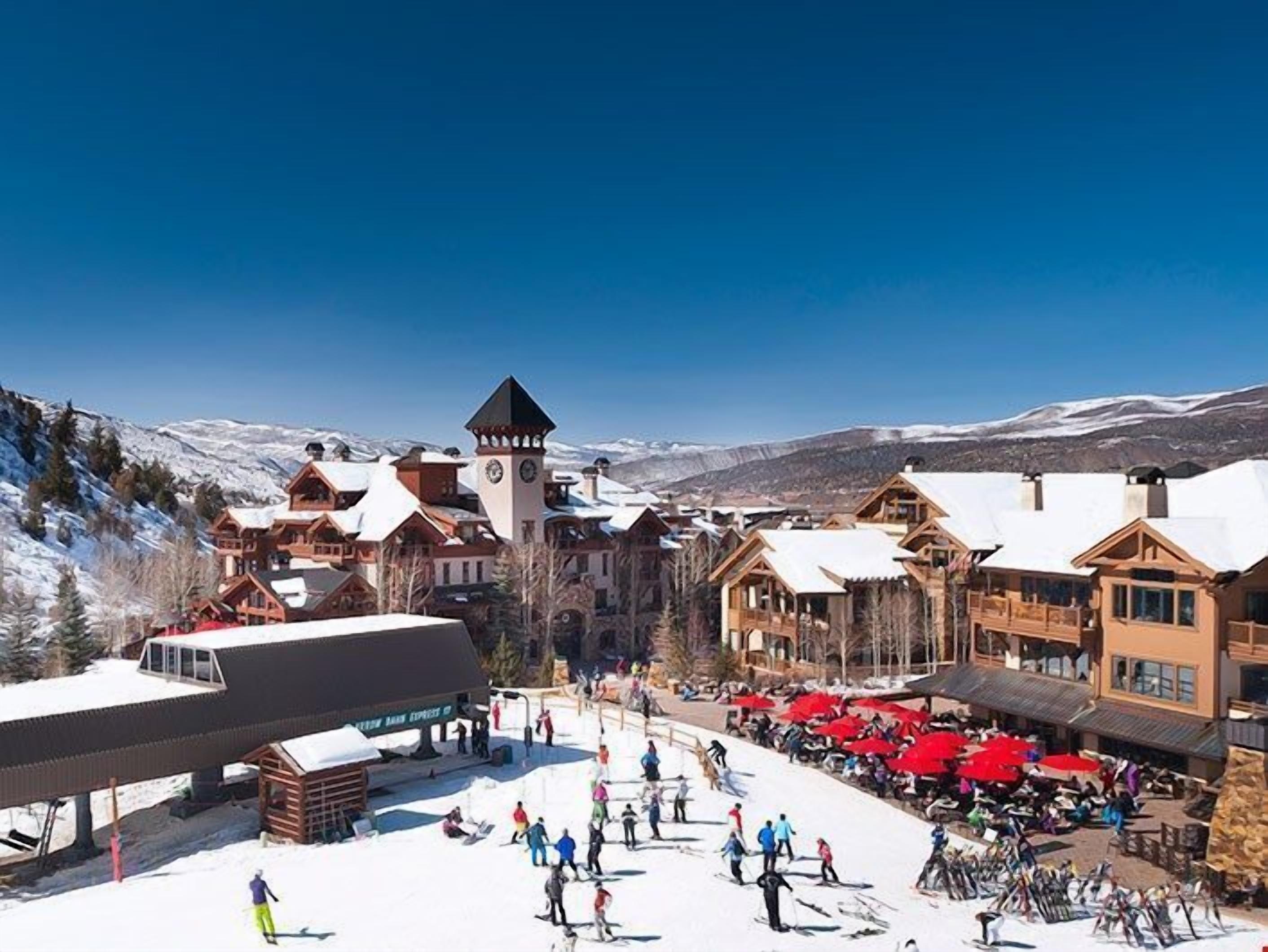 A ski resort with wooden buildings, a clock tower, and a snow-covered landscape.