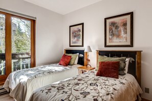 Two single beds with floral-patterned bedding, a large window, and framed artworks adorn this inviting bedroom.