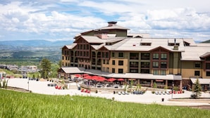 Un hotel de varios pisos con un patio, mobiliario exterior y vistas del paisaje circundante.