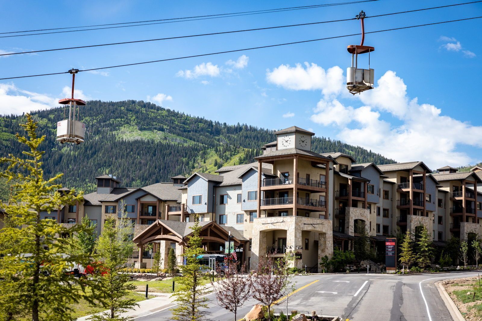 A multi-story hotel with balconies, a ski lift, and a mountainous backdrop.