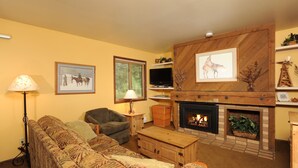 A living room with a fireplace, a sofa, a television, and framed artwork on the walls. - Mountain Studio for 2 with Fireplace (Keystone)