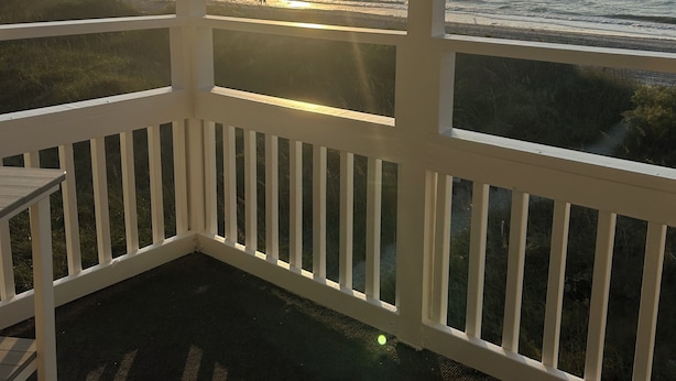 Un balcon avec vue sur l’océan au coucher du soleil.
