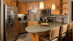 A modern kitchen with wooden cabinets, stainless steel appliances, and a granite countertop. - Cozy Condo + Gas Fireplace | Enjoy Ski-in/Ski-out (Park City)