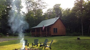 A cabin with a fire pit in the yard, surrounded by Adirondack chairs. - Upscale Cozy Cabin in the Woods, LETCHWORTH, Stony Brook Parks, Wineries (Dalton)