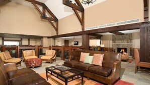 A spacious living room with a fireplace, leather sofas, and a coffee table. - Ski-In Alpine Condo + Balcony | Great Location (Breckenridge)