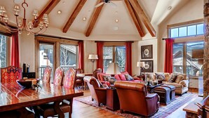 A spacious living room with a wooden dining table, leather sofas, and a chandelier. - Huge Mountain Condo with Fireplace & Balcony (Edwards)