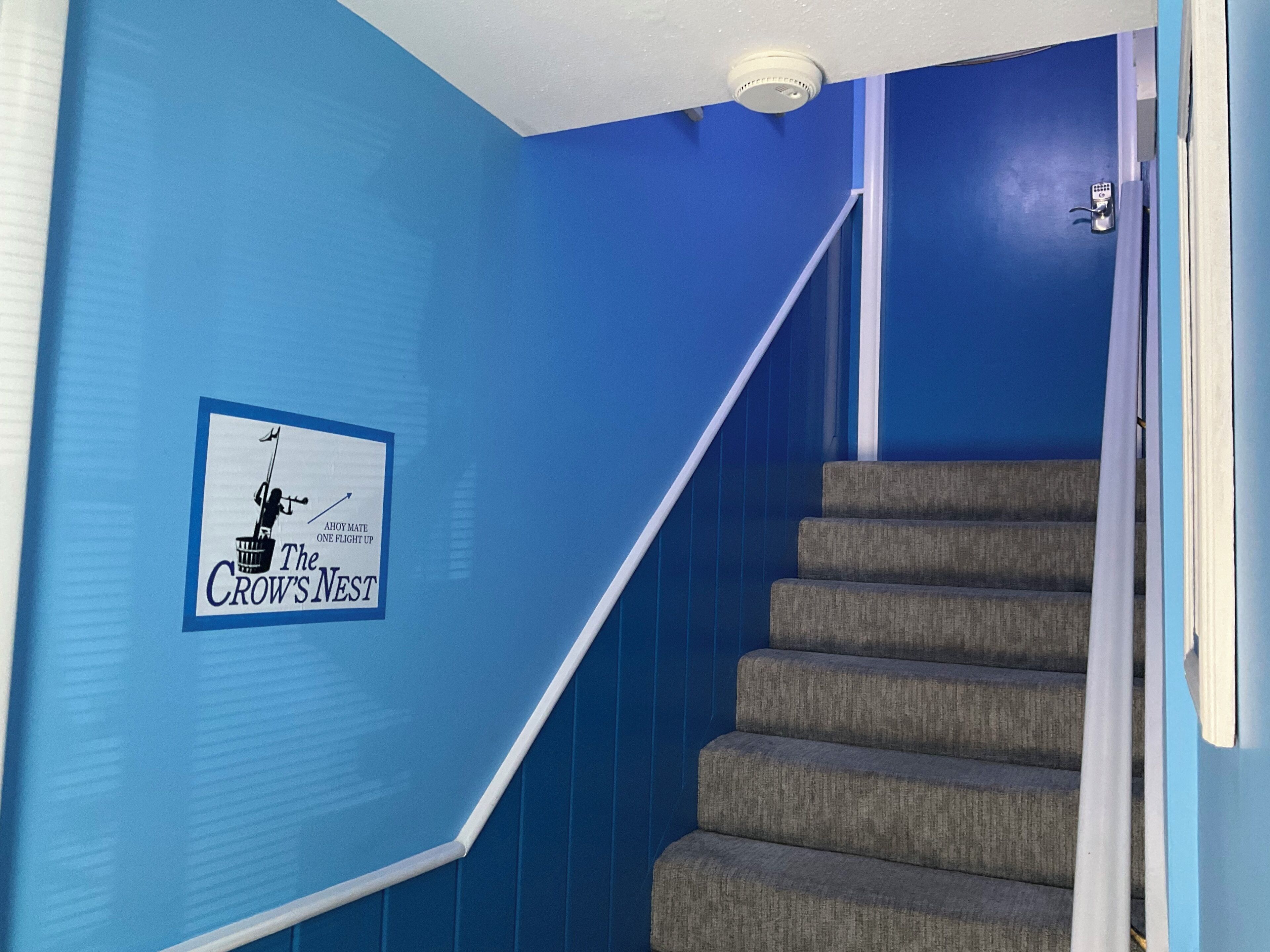 A staircase with a blue wall and a sign reading 'The Crow's Nest.'