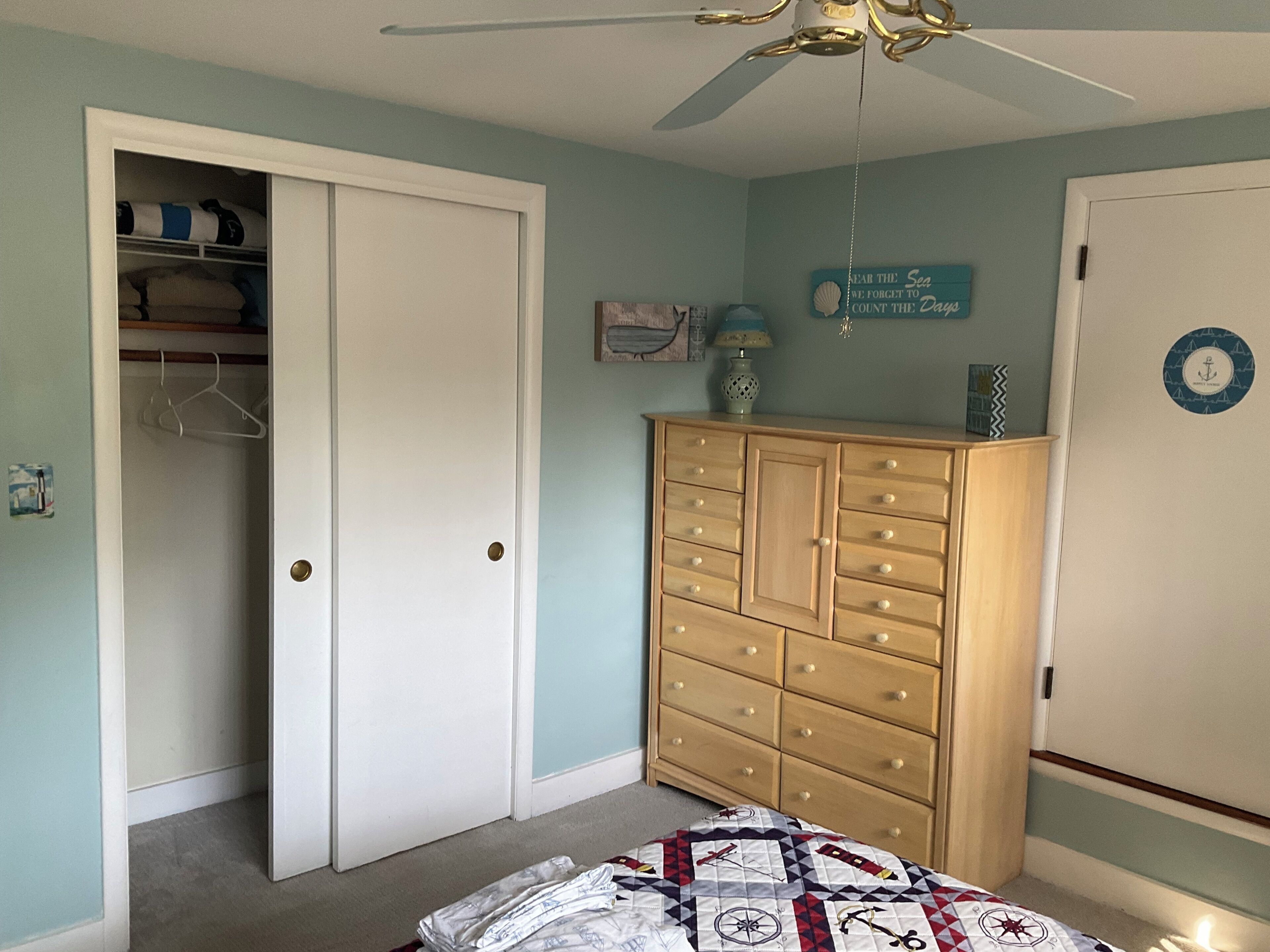 A bedroom with a closet, a dresser, and a bed.