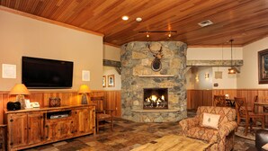 A cozy living room with a stone fireplace, wooden furniture, and a flat-screen TV. - Alpine Getaway + Balcony | Gym, Sauna, Hot Tub (Keystone)