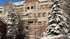 Un immeuble à plusieurs étages, doté de balcons, qui se dresse au milieu d’un paysage enneigé.