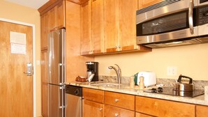 Une cuisine dotée de meubles en bois, d’appareils électroménagers en acier inoxydable, d’un plan de travail en granit et d’un four à micro-ondes encastré.