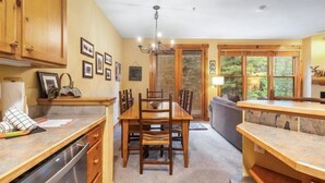A kitchen with wooden cabinets, a dining table, and chairs. There is a dishwasher and a countertop with a sink. - Cozy Mountain Getaway for 4 with Amazing Amenities (Dillon)