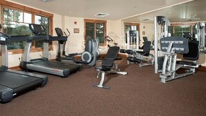 A gym with treadmills, weight machines, and a mirror wall. - Lovely 2 Bedroom Condo (Breckenridge)