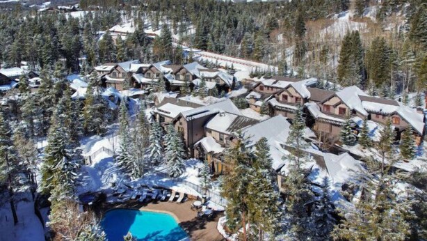 A snow-covered resort with multiple buildings, a swimming pool, and a mountainous backdrop. - Lovely 2 Bedroom Condo (Breckenridge)