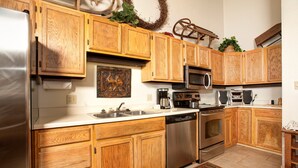Una cocina con armarios de madera, electrodomésticos de acero inoxidable y un adorno festivo.