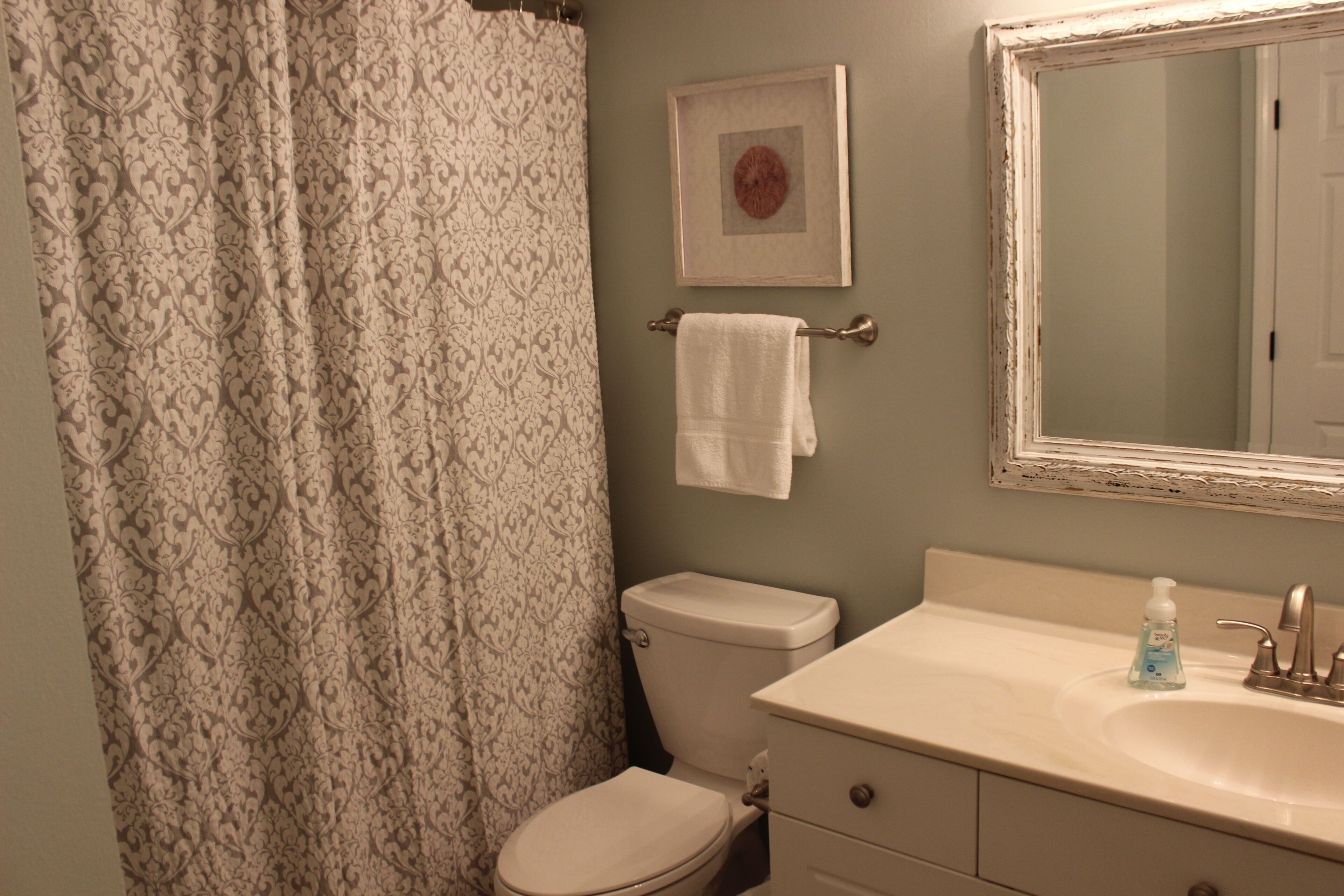 A bathroom with a toilet, sink, and a mirror.