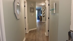 Un couloir doté d’un plancher en bois, de murs blancs et d’une porte équipée d’un clavier pour l’ouverture à code.