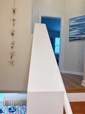 Une plateforme blanche, étroite et surélevée, avec un escalier menant à une porte.