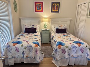 Une chambre à coucher avec deux lits, chacun agrémenté d’une couvre-lit à motifs uniques sur le thème du monde sous-marin.