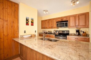 Kitchen features stainless steel appliances, a large island with a sink and a bowl, and ample countertop space.