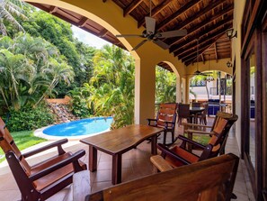Un espace patio avec une piscine, des meubles en bois et un ventilateur de plafond.