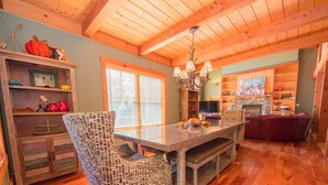 A dining area with a wooden table, patterned chairs, and a chandelier. -  Sleeps 20! Minutes to Main St & Lakes HotTub PoolTable Pingpong FirePit AC (Lake Placid)