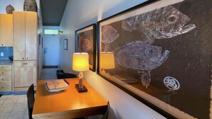Un comedor con una mesa de madera, sillas, una lámpara y cuadros de peces en la pared.