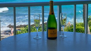 Una botella de Veuve Clicquot Brut champagne y dos copas sobre una mesa con vista a una playa y el océano.