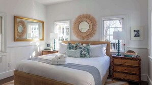 Une chambre à coucher bien rangée, avec un grand lit, deux tables de chevet et un miroir.