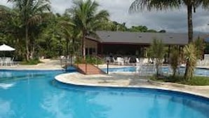 A swimming pool with lounge chairs and palm trees. - Cond Hanga Roa - Bertioga Riviera (Bertioga)