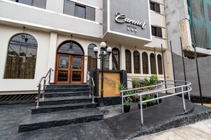 L’entrée d’un hôtel, avec un escalier en marbre, une porte en bois et une enseigne indiquant « Hôtel Carnel ».