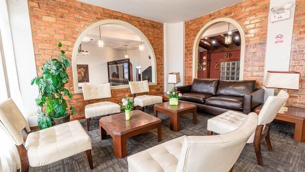 A spacious living area with a brick wall, leather sofa, and multiple seating options. - Hotel Carmel (Lima)