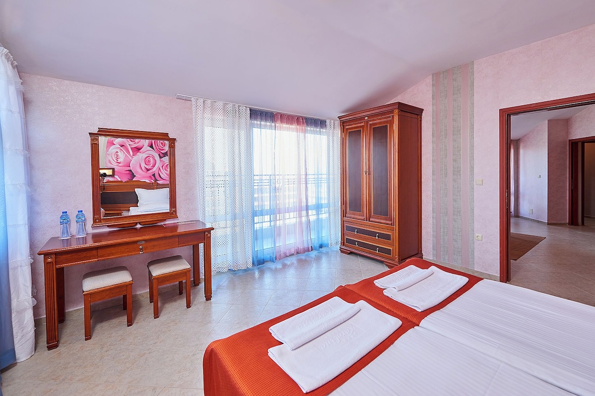 A hotel room with a bed, a desk, a chair, a wardrobe, and a mirror.