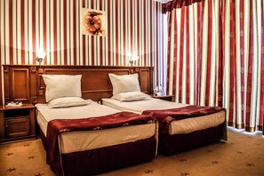Une chambre d’hôtel avec deux lits, des têtes de lit en bois et des rideaux à rayures.