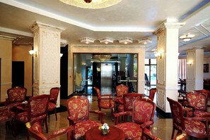 A lobby with ornate red chairs, a chandelier, and a glass door leading to another area. - Karolina (Nessebar)