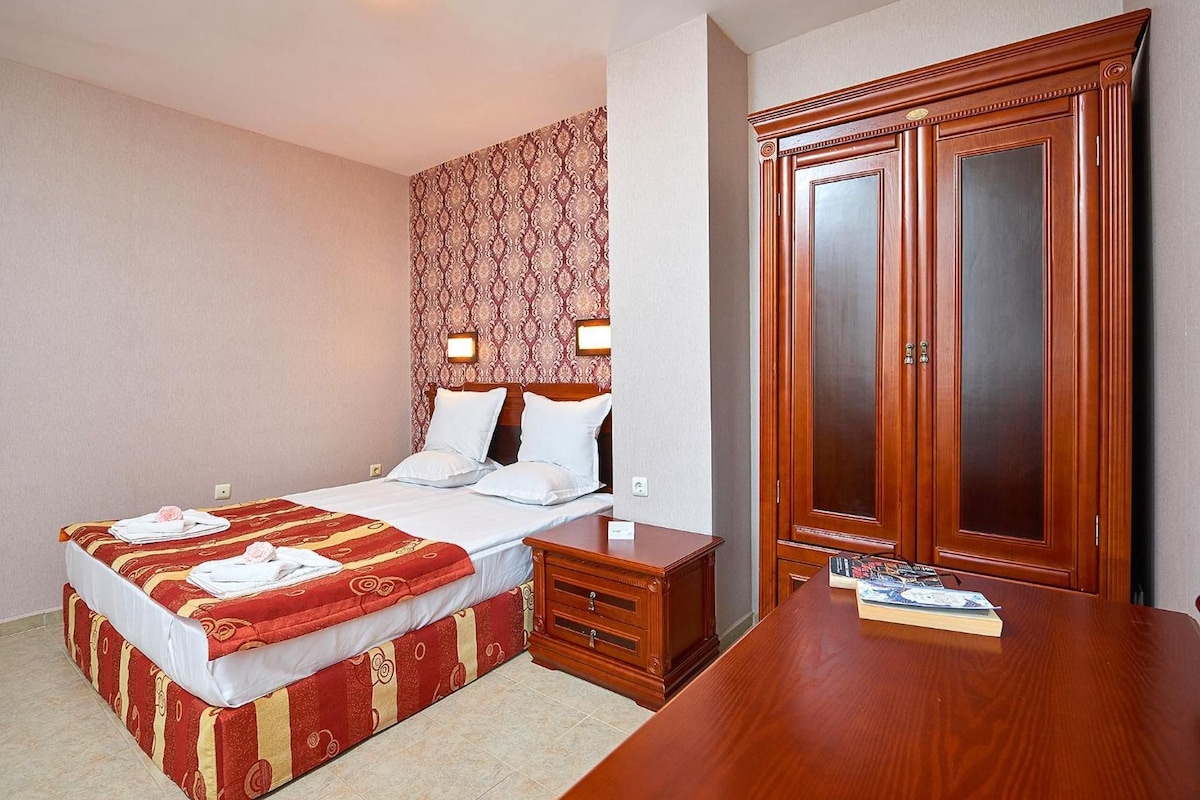 A hotel room with a bed, bedside table, and a wardrobe.