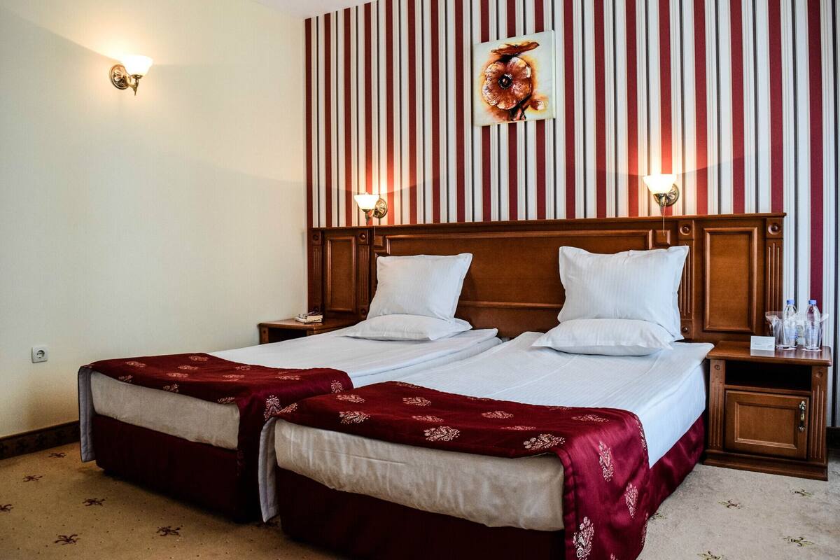 A double bed with a wooden headboard, two bedside tables, and a red and white striped wall.