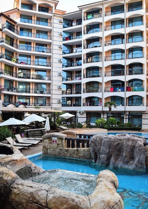 Un hotel de diverses plantes amb balcons, una piscina i zones d'estar a l'aire lliure.
