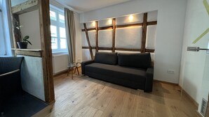 A modern living room with a wooden floor, a dark grey sofa, and a small side table. - Stella Apartments (Erfurt)